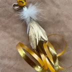 Christmas Cat Gift with golden feathers, ribbons, and a jingle bell for playful feline fun.