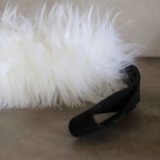 Close-up of a soft Australian sheepskin Dog Tug Toy with a black handle.
